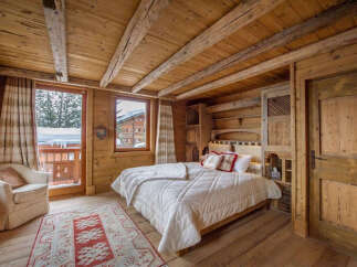 Experience the rustic charm of this cozy bedroom, featuring warm wooden walls and a beamed ceiling.