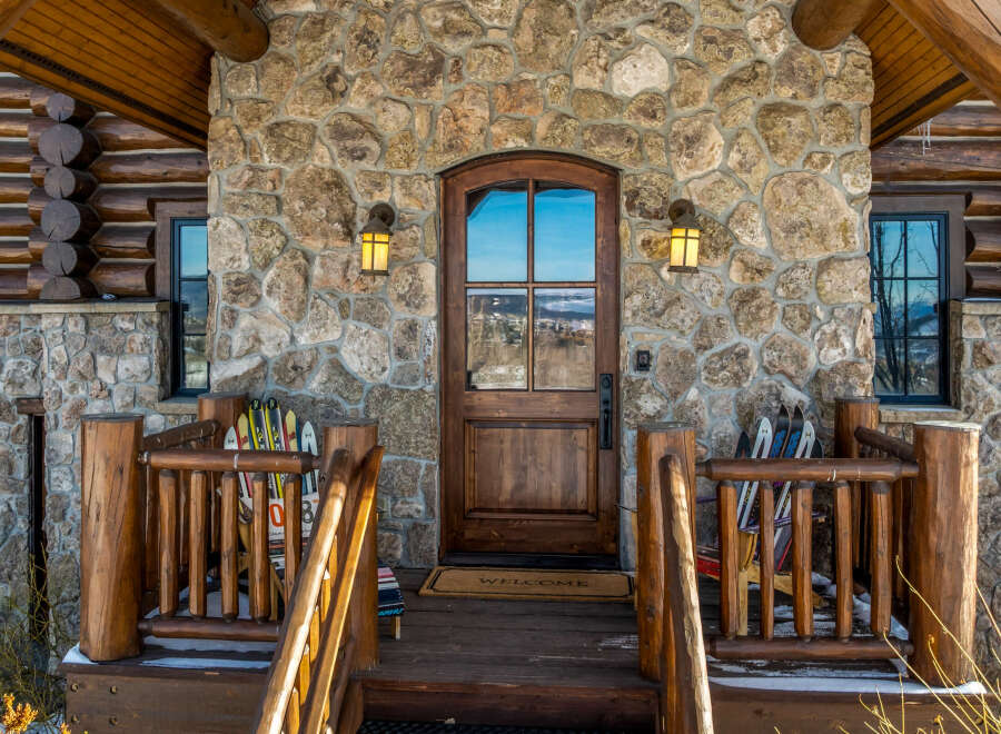 This stunning mountain home boasts a beautiful stone facade and a welcoming wooden door.