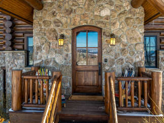 This stunning mountain home boasts a beautiful stone facade and a welcoming wooden door.