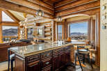 Experience the rustic charm of this stunning log cabin kitchen, featuring a beautiful island with a granite countertop and dark wood cabinetry.
