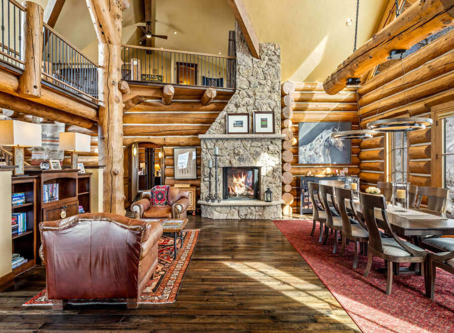 Experience rustic luxury in this stunning log home, featuring a grand stone fireplace and exposed wooden beams.