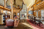 Experience rustic luxury in this stunning log home, featuring a grand stone fireplace and exposed wooden beams.