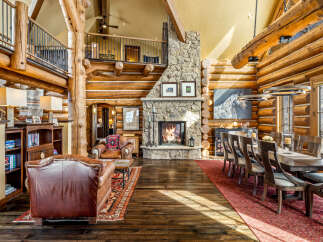 Experience rustic luxury in this stunning log home, featuring a grand stone fireplace and exposed wooden beams.