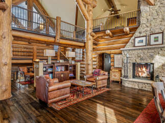 Experience rustic luxury in this stunning log home, featuring a grand stone fireplace and soaring ceilings.