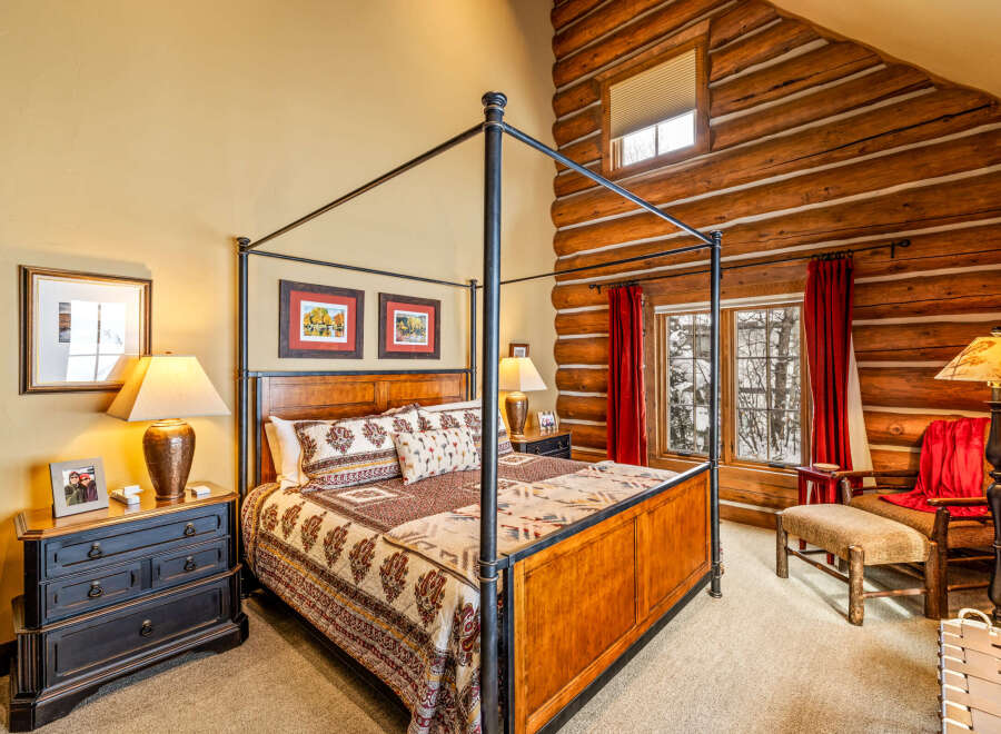 Step into luxury with this stunning bedroom featuring a majestic four-poster bed and rustic log cabin accents.