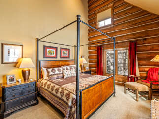 Step into luxury with this stunning bedroom featuring a majestic four-poster bed and rustic log cabin accents.