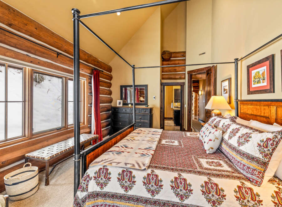 Experience rustic charm in this stunning bedroom featuring a four-poster bed and log cabin-style walls.