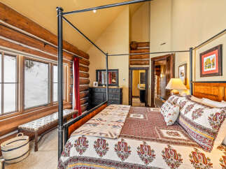 Experience rustic charm in this stunning bedroom featuring a four-poster bed and log cabin-style walls.