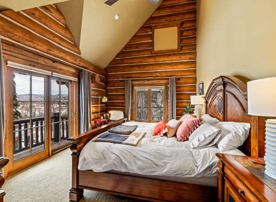 Experience rustic luxury in this stunning bedroom featuring exposed log walls and a cozy ambiance.