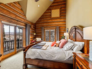 Experience rustic luxury in this stunning bedroom featuring exposed log walls and a cozy ambiance.