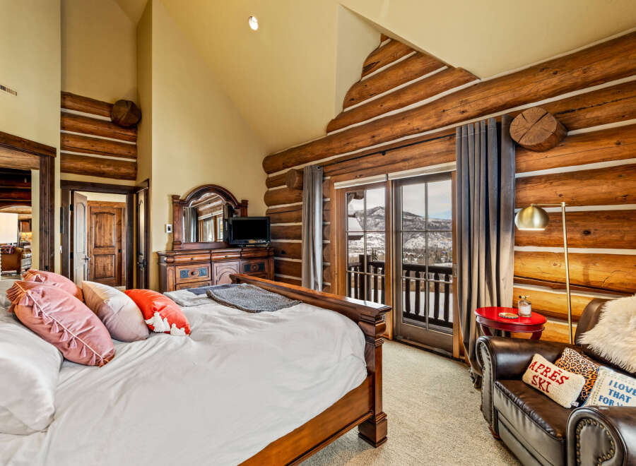 Experience luxury living in this stunning bedroom featuring rustic log accents and a cozy ambiance.