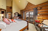 Experience luxury living in this stunning bedroom featuring rustic log accents and a cozy ambiance.