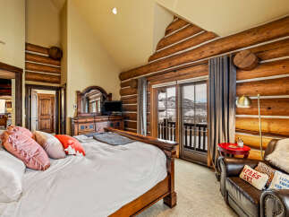 Experience luxury living in this stunning bedroom featuring rustic log accents and a cozy ambiance.