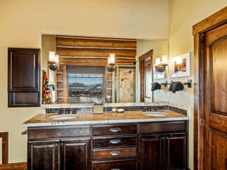 This stunning bathroom features a luxurious double vanity with a granite countertop and dark wood cabinetry.