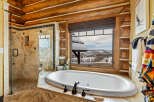 Indulge in the luxury of this stunning bathroom, featuring a serene soaking tub and a breathtaking view of the winter landscape.