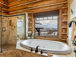 Indulge in the luxury of this stunning bathroom, featuring a serene soaking tub and a breathtaking view of the winter landscape.