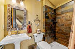 This stunning bathroom boasts a rustic charm with its stone-tiled shower and decorative mirror.