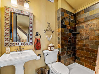 This stunning bathroom boasts a rustic charm with its stone-tiled shower and decorative mirror.