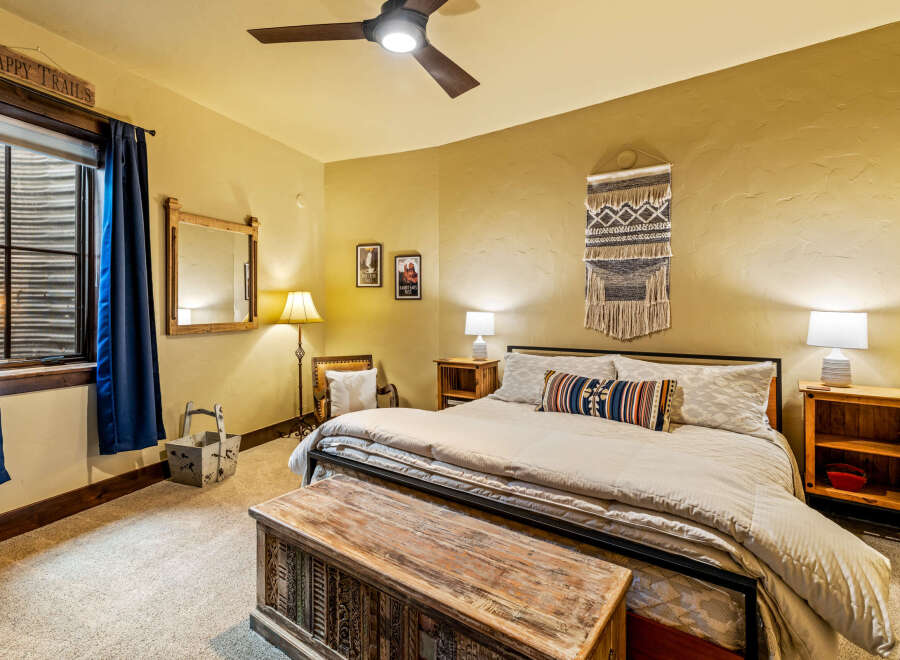 This cozy bedroom features a rustic aesthetic with a wooden chest at the foot of the bed.