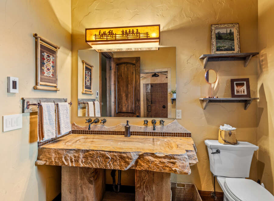 This rustic bathroom showcases a unique stone sink and a wooden vanity, creating a warm and inviting atmosphere.