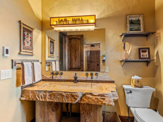 This rustic bathroom showcases a unique stone sink and a wooden vanity, creating a warm and inviting atmosphere.