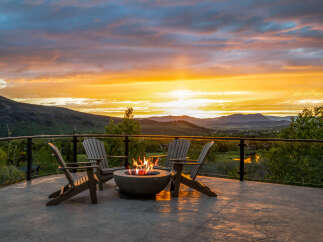 Enjoy breathtaking sunsets from this stunning property, featuring a cozy outdoor seating area with a fire pit.