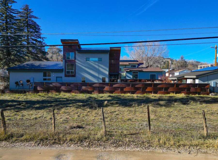 This stunning property boasts modern architecture with a unique, rust-colored metal facade, offering a striking visual appeal.