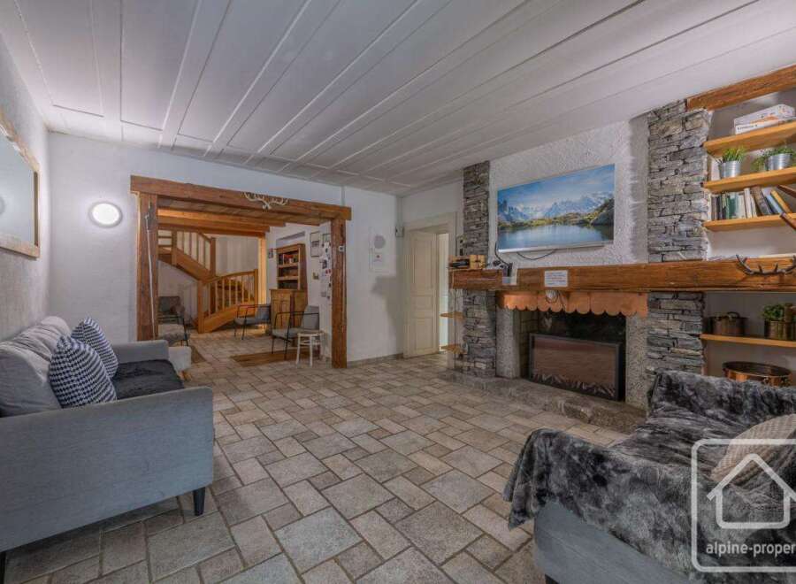 Discover the charm of this stunning property, featuring a cozy living room with a stone fireplace and a mounted TV.