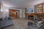 Discover the charm of this stunning property, featuring a cozy living room with a stone fireplace and a mounted TV.