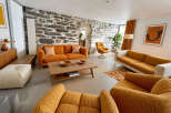 Experience unique living in this stunning living room, featuring a striking stone accent wall and vibrant orange sofas.