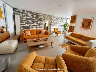 Experience unique living in this stunning living room, featuring a striking stone accent wall and vibrant orange sofas.