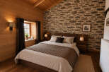 Experience rustic charm in this cozy bedroom, featuring a beautiful stone accent wall and warm wooden paneling.