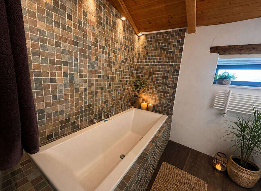 Indulge in relaxation in this luxurious bathroom featuring a deep soaking tub surrounded by elegant mosaic tilework.