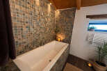 Indulge in relaxation in this luxurious bathroom featuring a deep soaking tub surrounded by elegant mosaic tilework.