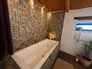 Indulge in relaxation in this luxurious bathroom featuring a deep soaking tub surrounded by elegant mosaic tilework.