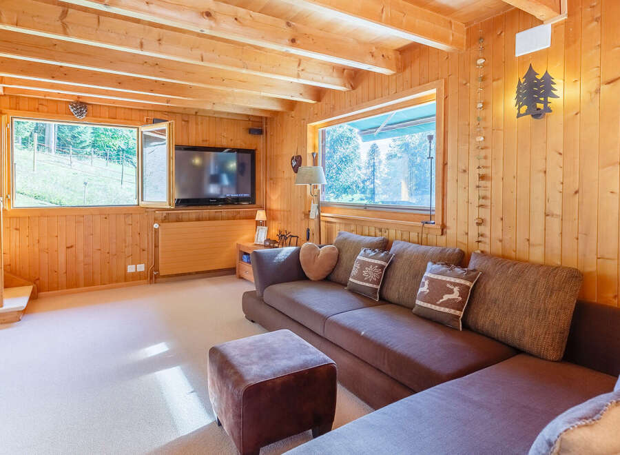 Step into this cozy cabin retreat, featuring warm wood paneling and a comfortable living space.