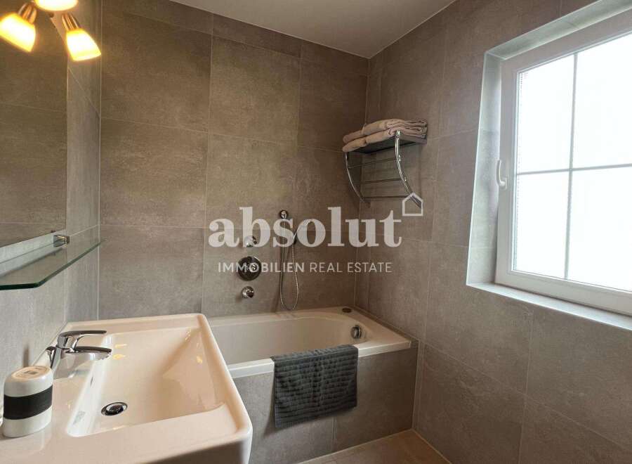 Discover a modern bathroom design featuring a sleek bathtub, a stylish sink, and elegant tile work.
