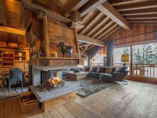 Experience the warmth of this stunning chalet, featuring a grand fireplace and exposed wooden beams that create a cozy atmosphere.