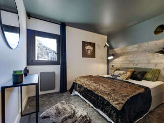 Experience the cozy charm of this bedroom, featuring a rustic wooden headboard and a plush, inviting bedspread.