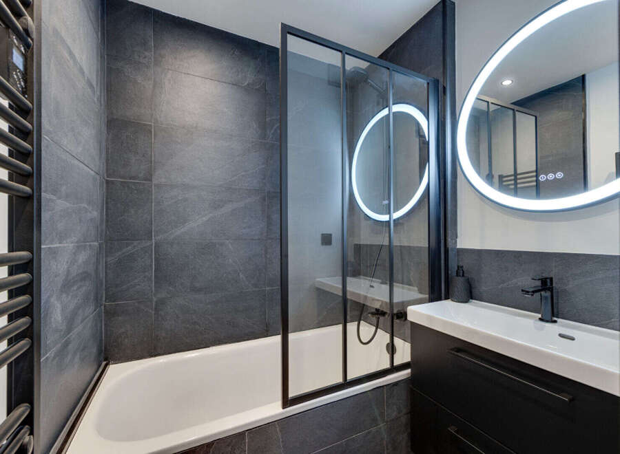 This modern bathroom features sleek, dark gray tiles and a minimalist design.