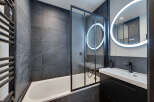 This modern bathroom features sleek, dark gray tiles and a minimalist design.