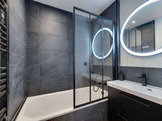 This modern bathroom features sleek, dark gray tiles and a minimalist design.