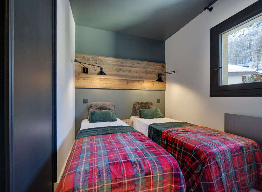 Cozy bedroom featuring two twin beds with vibrant plaid bedding, perfect for a comfortable stay.