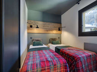 Cozy bedroom featuring two twin beds with vibrant plaid bedding, perfect for a comfortable stay.