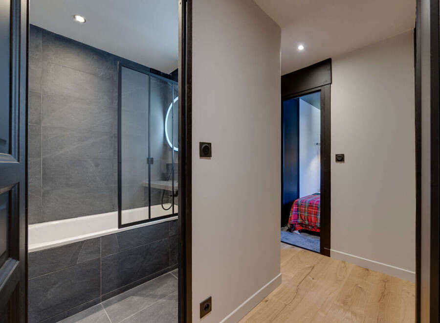Step into modern elegance with this stunning property, featuring a beautifully designed bathroom with sleek gray tiles and a glass shower enclosure.