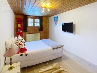 This cozy bedroom features a warm wooden ceiling and walls, creating a rustic and inviting atmosphere.