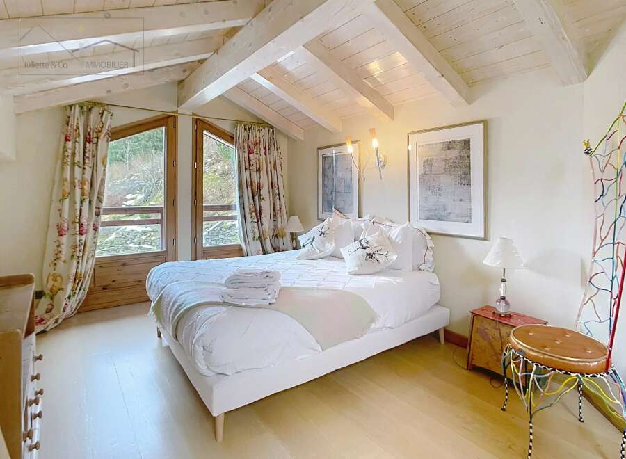 This charming bedroom features a cozy ambiance with its wooden ceiling and natural light.