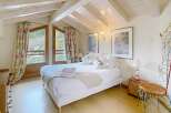 This charming bedroom features a cozy ambiance with its wooden ceiling and natural light.