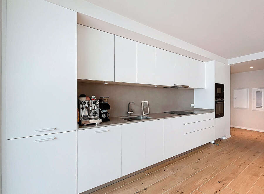 This modern kitchen boasts sleek, white cabinetry and a minimalist design, perfect for contemporary living.