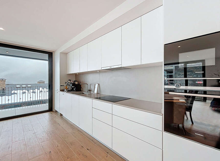 This modern kitchen boasts sleek white cabinetry and stainless steel appliances, creating a clean and contemporary aesthetic.
